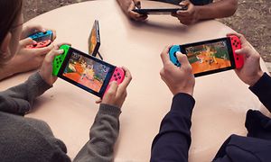Lapset istuvat pöydän ääressä pelaten Nintendo Switchiä