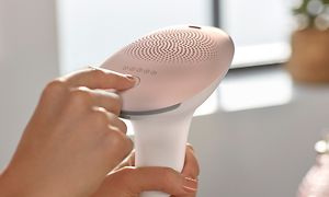 Käsi painaa Philips IPL -karvojenpoistolaitteen painiketta