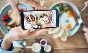 Henkilö ottaa kuvaa ruoka-annoksesta älypuhelimen kameralla