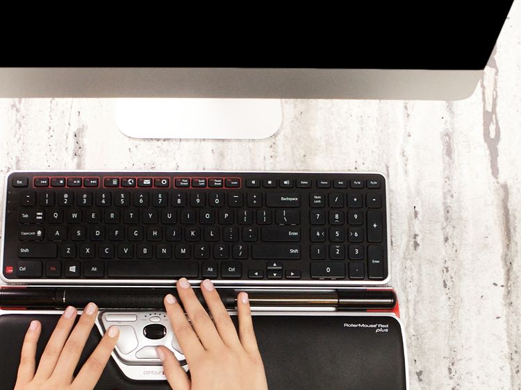 Henkilö työskentelee Contour RollerMouse-hiirellä ja -näppäimistöllä, vieressä Contour-logo