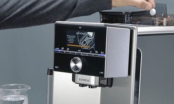 Henkilö laittaa puhdistustablettia Siemens-espressokeittimeen