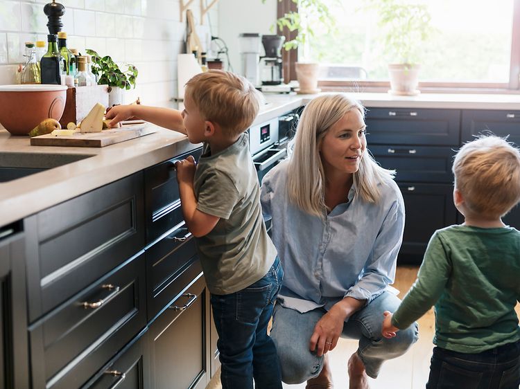 Äiti ja kaksi lasta modernissa keittiössä