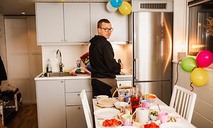 Mies pienessä keittiössä, jossa on jääkaappipakastin