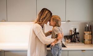 Äiti ja lapsi halaavat toisiaan modernissa keittiössä