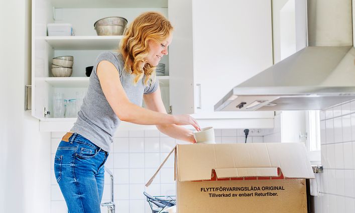 Nainen purkaa muuttolaatikkoa keittiössä