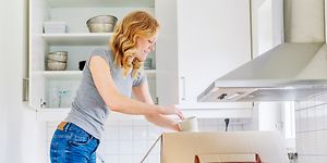 Nainen purkaa muuttolaatikkoa keittiössä