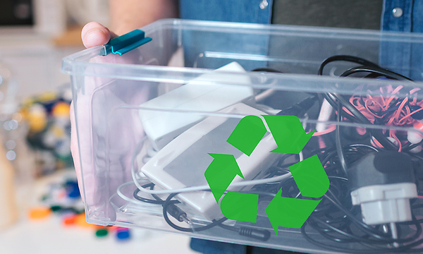 Mies pitelee laatikkoa jossa vanhaa elektroniikkaa ja kierrätyssymboli
