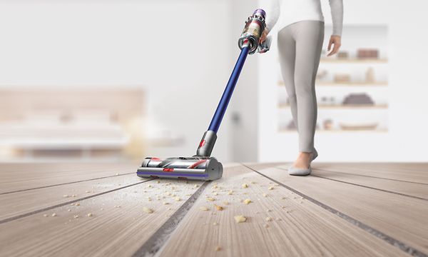 Nainen imuroi muruja puulattialta Dyson-pölynimurilla