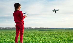 Nainen lennättää dronea avoimella kentällä