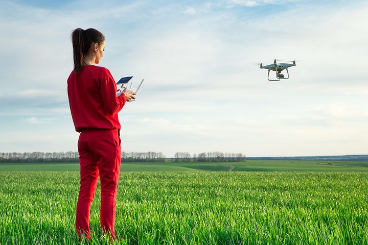 Nainen lennättää dronea avoimella kentällä