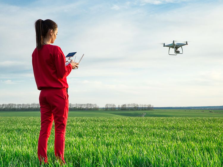 Nainen lennättää dronea avoimella kentällä