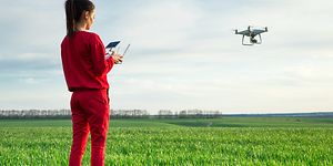 Nainen lennättää dronea avoimella kentällä