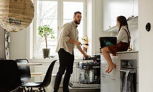 Mies laittaa ruokailuvälineitä astiapesukoneen erilliselle aterintasolle