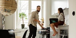 Mies laittaa ruokailuvälineitä astiapesukoneen erilliselle aterintasolle
