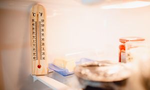 Avoin jääkaappi, jossa erilaisia ruokia ja lämpömittari etualalla