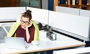 Nainen työskentelee toimistossa vaaleanvihreä peite hartioillaan