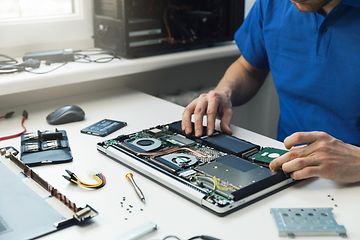 Tietokoneet - Mies korjaa kannettavan tietokoneen SSD-levyä