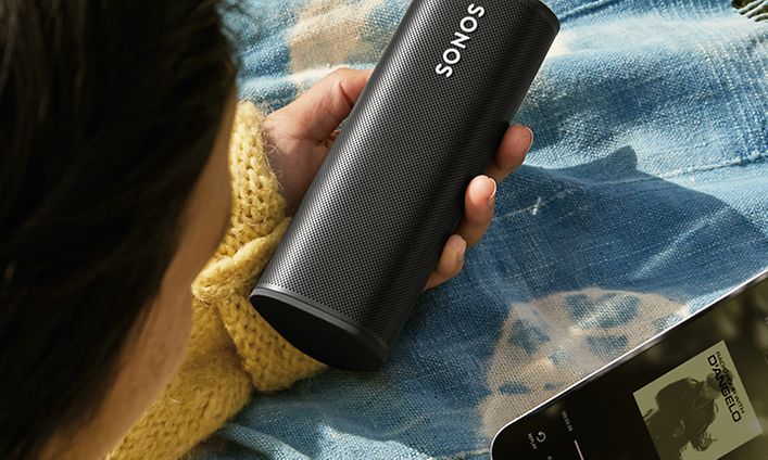 Nainen, jolla on Sonos Roam ja puhelin