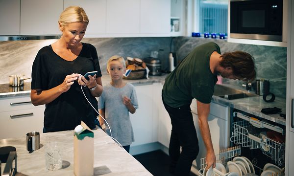 Perhe keittiössä astianpesukoneen vieressä