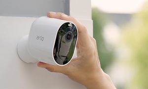 Käsi asettamassa Arlo Pro3 -kameraa seinään