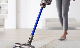 Nainen imuroi mattoa Dyson V11 -varsi-imurilla