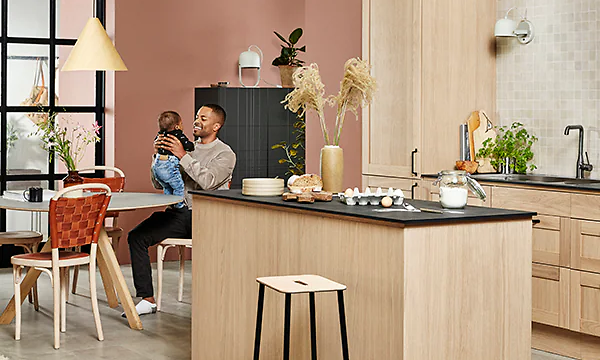 Mies ja vauva istuvat Natural Oak -puukuvioisessa Epoq Shaker -keittiössä