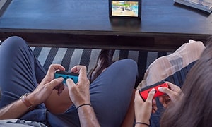 Nintendo Switch - kaksi henkilöä pelaa pöydällä olevalla laitteella sekä joycon-ohjaimilla