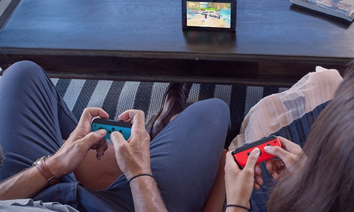 Nintendo Switch - kaksi henkilöä pelaa pöydällä olevalla laitteella sekä joycon-ohjaimilla