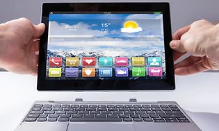 Two hands holding a 2-in-1 PC with removable keyboard