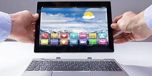 Two hands holding a 2-in-1 PC with removable keyboard