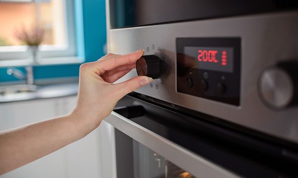 Käsi säätää uunin lämpötilaa