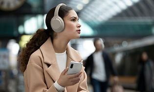 Nainen metrossa Sony WH-1000XM4 -kuulokkeet korvillaan
