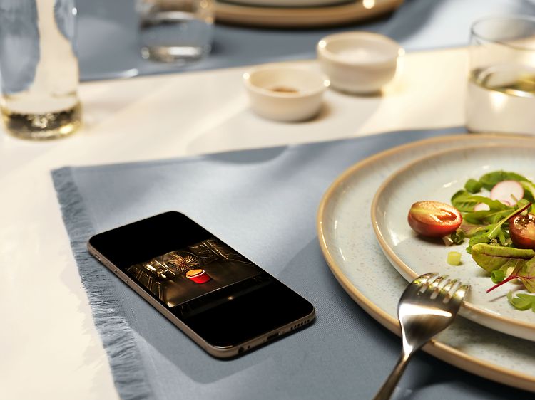 Keittiön pöydällä oleva matkapuhelin, jonka näytöllä näkyy uunin sisältö