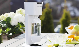 Valkoinen Sodastream puutarhapöydällä sitrushedelmien vieressä