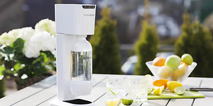 Valkoinen Sodastream puutarhapöydällä sitrushedelmien vieressä