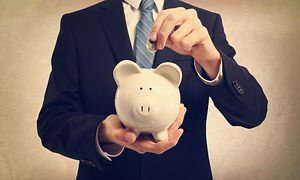 Man in a suit putting coin in a moneybox
