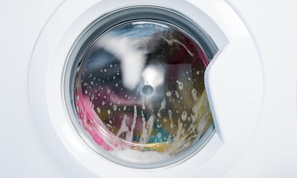 pyykinpesukone, jonka sisällä on värikästä pyykkiä