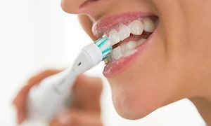 Sähköhammasharja - lähikuva henkilöstä pesemässä sähköhammasharjalla hampaitaan