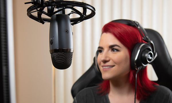 Nainen tallentaa podcastin Blue Yeti Nano -mikrofonilla.
