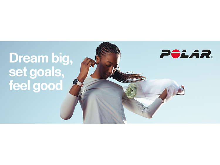 Polar-urheilukello naisen ranteessa ja teksti Dream big set goals feel good