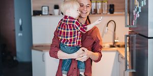 Isä pitelee pientä poikaansa sylissään, joka tutkii jääkaapin oveen kiinnitettyjä magneetteja