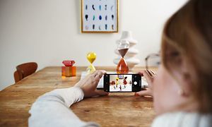 Nainen ottaa kuvaa pöydällä olevista esineistä iPhonellaan