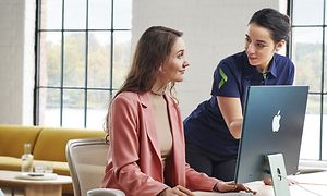  Naispuolinen Gigantin työntekijä auttaa naista iMacin käytössä