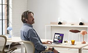 Mies istuu työpöydän ääressä MacBook edessään
