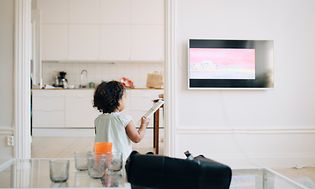 Pieni tyttö ohjaa televisiota kaukosäätimellä