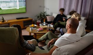 Family in sofa watching sports on TV