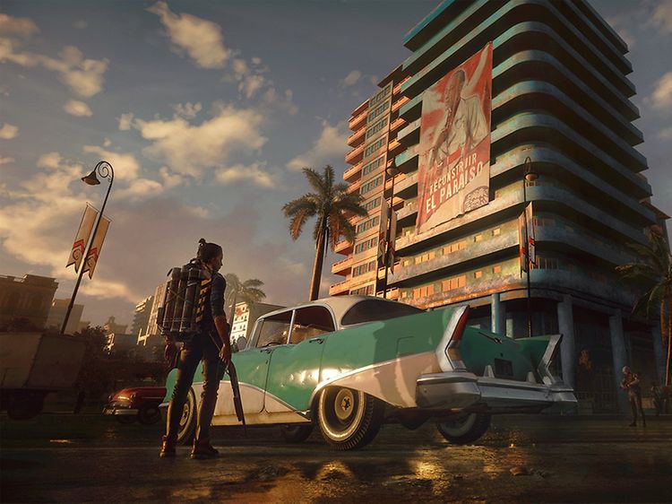 Far Cry 6 - Nainen liekinheitin kädessään seisoo auton vieressä korkean rakennuksen edessä