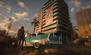 Far Cry 6 - Nainen liekinheitin kädessään seisoo auton vieressä korkean rakennuksen edessä