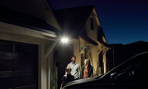 Perhe seisoo Floodlight-kameran valaisemalla terassilla