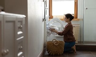 MDA - Kuivausrumpu - Nainen laittamassa pyykkiä kuivausrummun sisälle